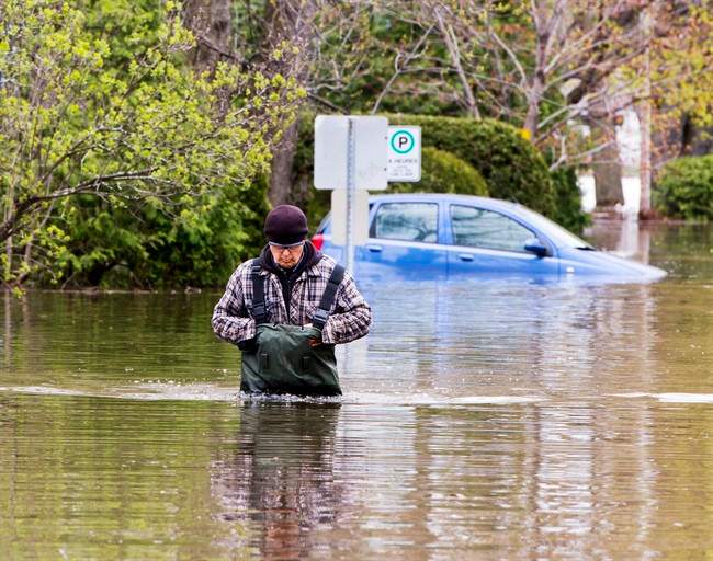 A resident walks through the flooded streets Tuesday, May 9, 2017 in Deux-Montagnes, Quebec.