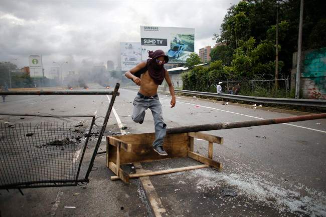 A demonstrator jumps over a barricade during a national sit-in against President Nicolas Maduro, in Caracas, Venezuela.