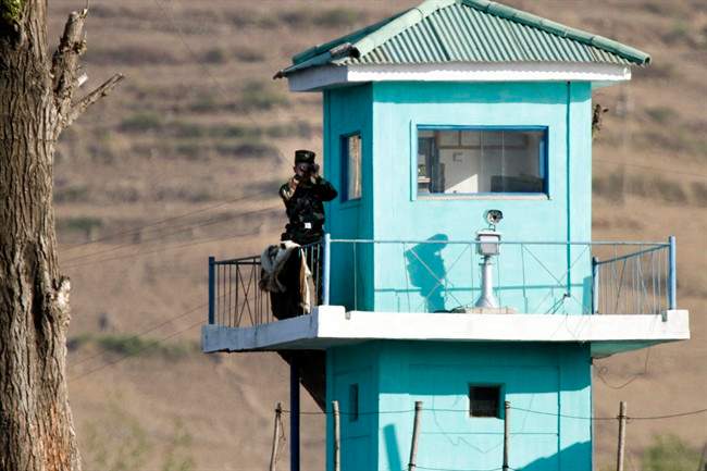 In this Wednesday, May 3, 2017 photo, a North Korean soldier looks through a pair of binoculars as he stands at a guard tower on the border near Chongsu in North Korea's North Pyongan Province.