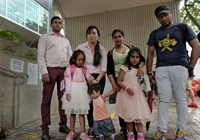 Asylum seekers, from left: Ajith Pushpa Kumara, Vanessa Mae Rodel and her daughter Keana, Nadeeka Dilrukshi Nonis and her son Dinath and daughter Sethmundi Kellapatha, and Supun Thilina Kellapatha, pose outside the building of Hong Kong’s immigration department in Hong Kong.