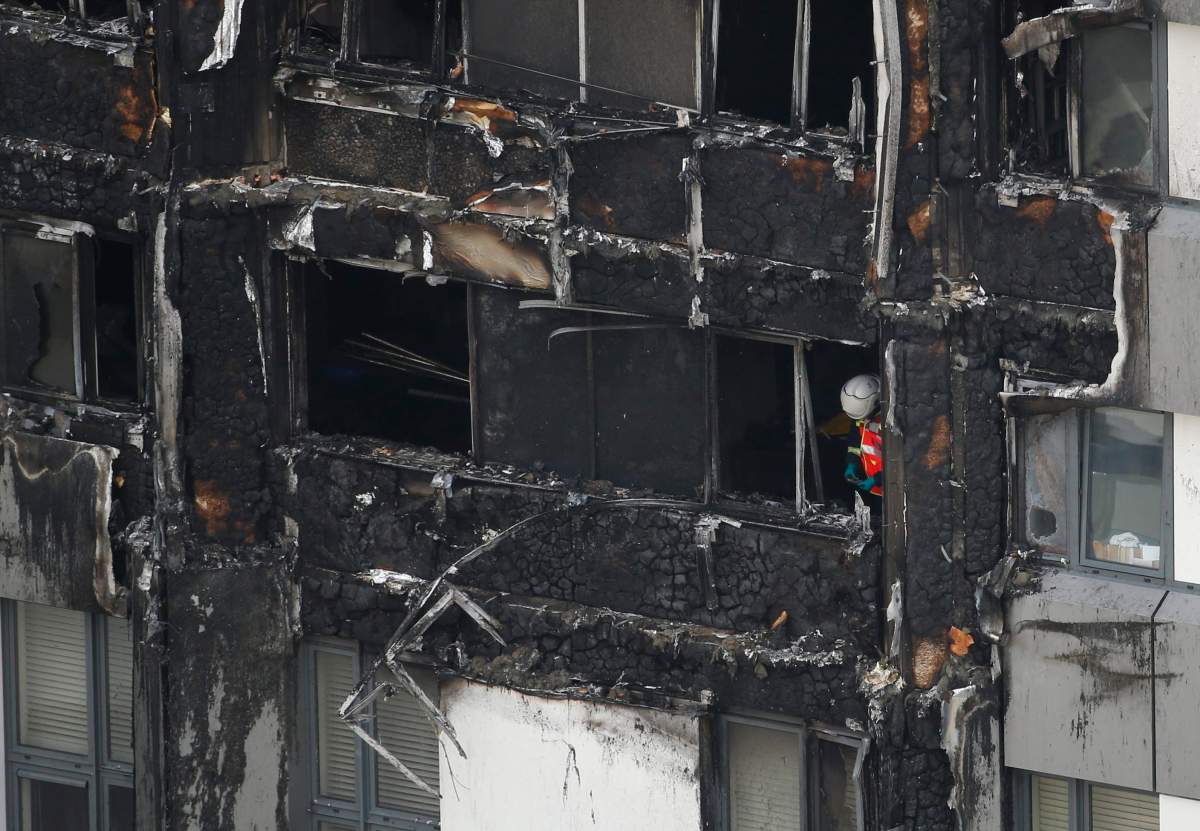 A fire officer looks at debris in a high rise apartment block on fire in London.