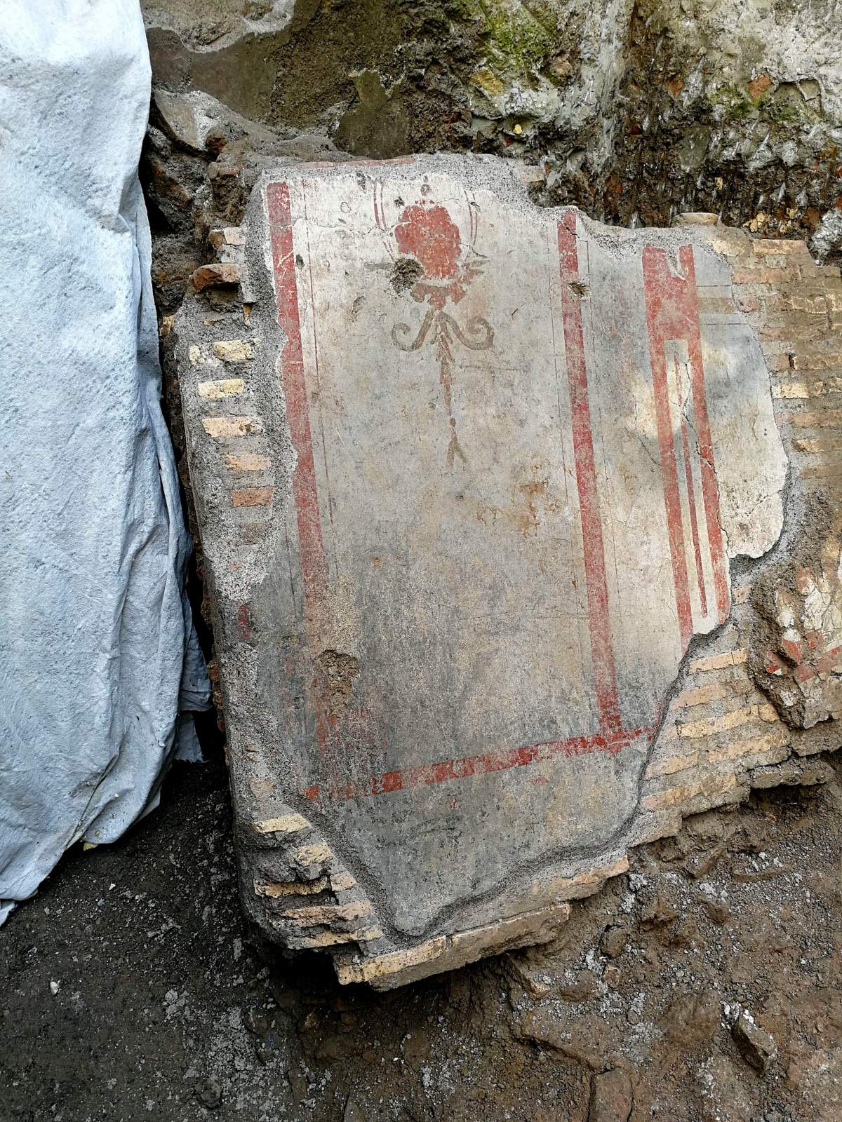 The frescoed wall segment, part of the charred ruins of a 3rd-century building.