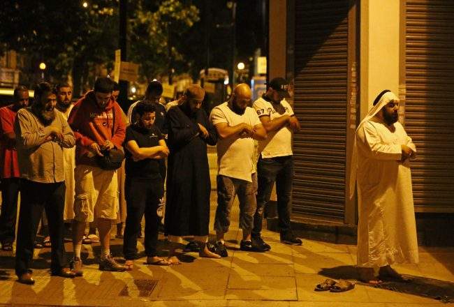 Men pray near the scene after a vehicle collided with pedestrians near a mosque in the Finsbury Park neighborhood of North London, Britain, June 19, 2017.