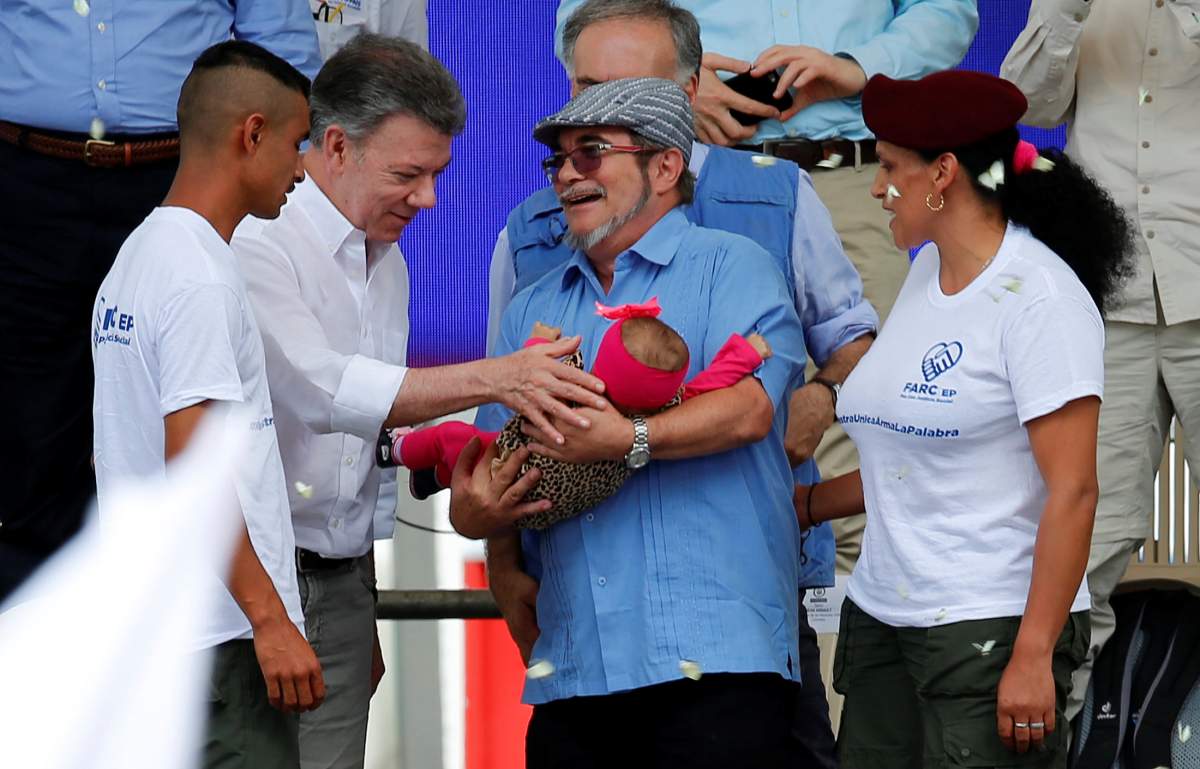 Colombia’s Marxist FARC rebel leader Rodrigo Londono, also known as Timochenko, holds a baby next to Colombian president Juan Manuel Santos as they attend the final act of abandonment of arms in Mesetas, Colombia June 27, 2017.