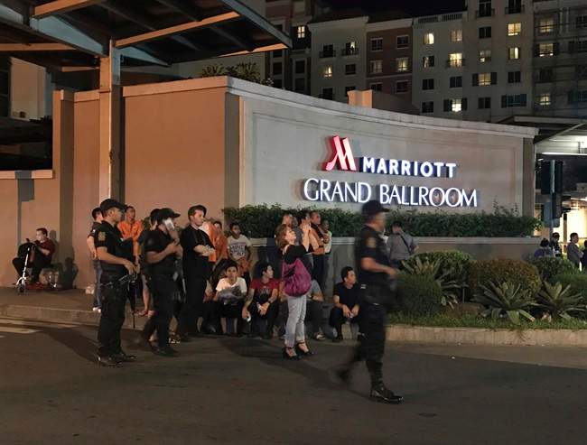 Armed security officers and onlookers gather outside a hotel at the Resorts World Manila complex, early Friday, June 2, 2017, in Manila, Philippines.