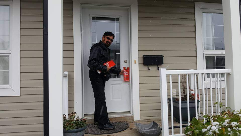 Brian Sklar hangs campaign material on a doorknob during his city council election campaign.