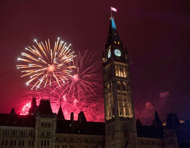 Fireworks light up the sky red behind the Peace Tower