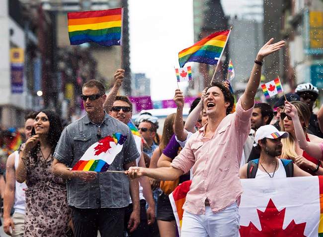 Prime Minister Justin Trudeau is splashed with water as he waves a flag at the annual Pride Parade in Toronto on Sunday, July 3, 2016.