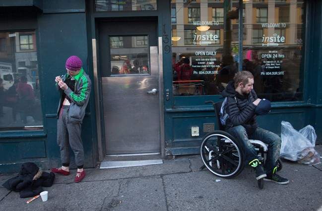 A woman, left, prepares to inject herself with an unknown substance outside Insite, the supervised consumption site, in the Downtown Eastside of Vancouver on Feb. 21, 2017.