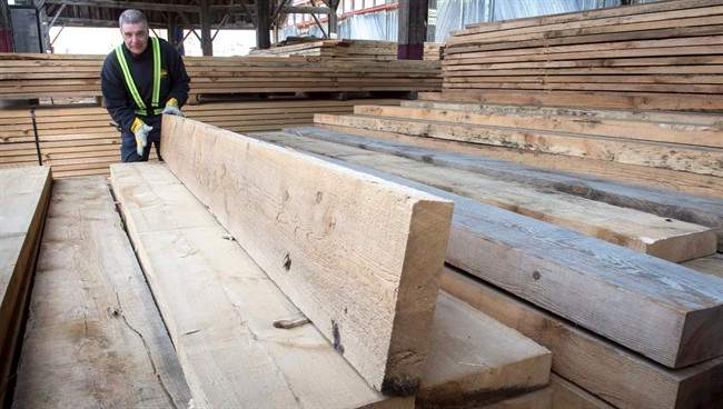A worker tidies up the wood pile at a lumber yard Tuesday, April 25, 2017 in Montreal. 