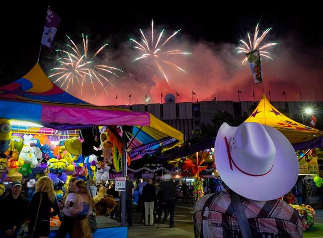 A visitor watches the fireworks display from the midway at the Calgary Stampede in Calgary, Saturday, July 9, 2016. 