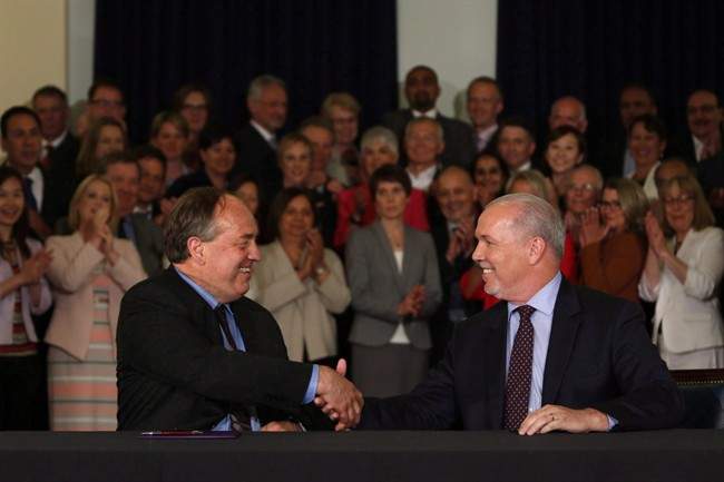 B.C. NDP Leader John Horgan and B.C. Green Party Leader Andrew Weaver shake hands during a press conference in the Hall of Honour at the Legislature in Victoria on May 30, 2017.