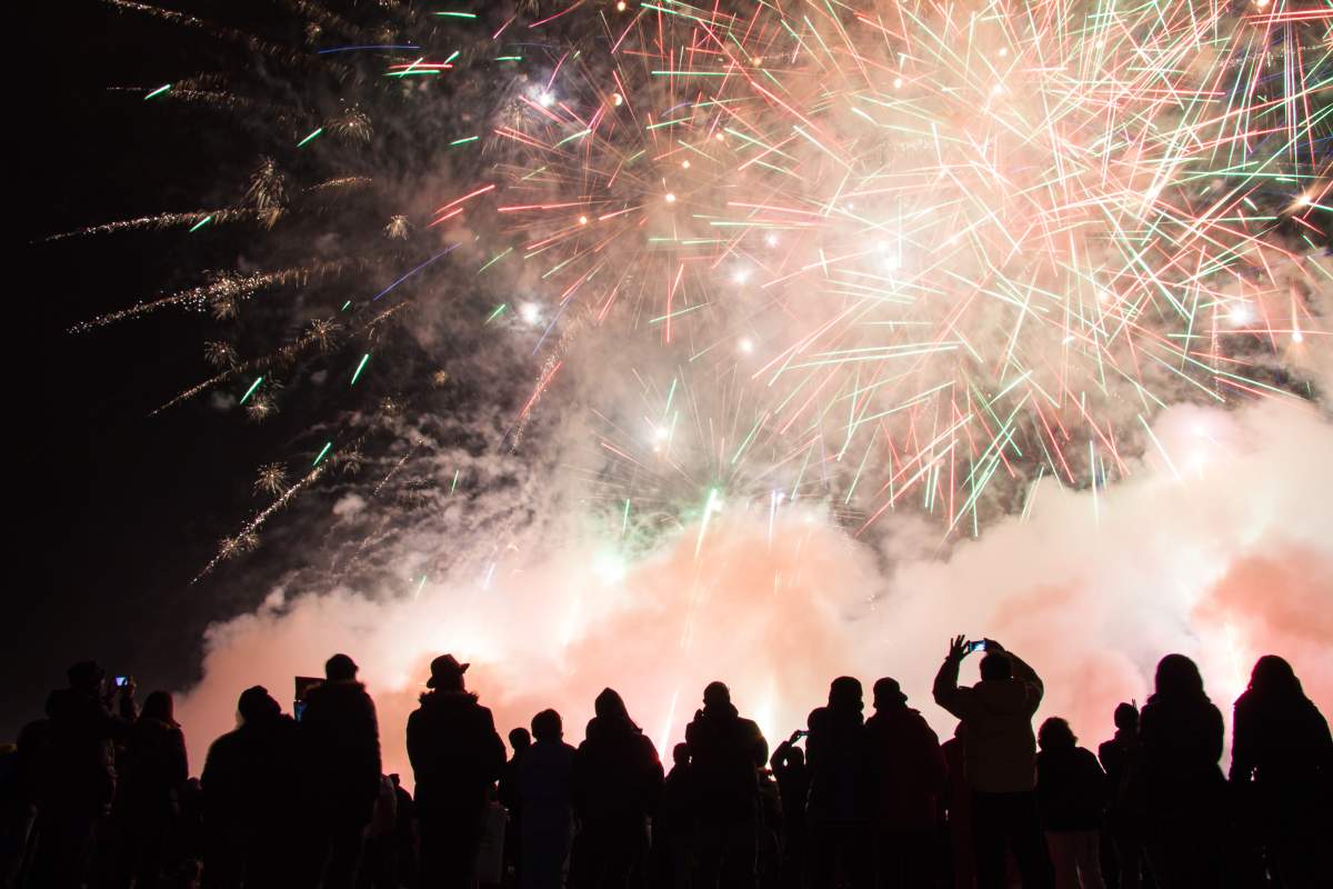 People watch and take photos of a fireworks display.