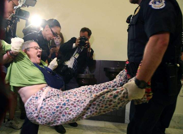 Police remove a woman from a protest in front of the office of Senate Majority Leader Mitch McConnell on Capitol Hill, on June 22, 2017.