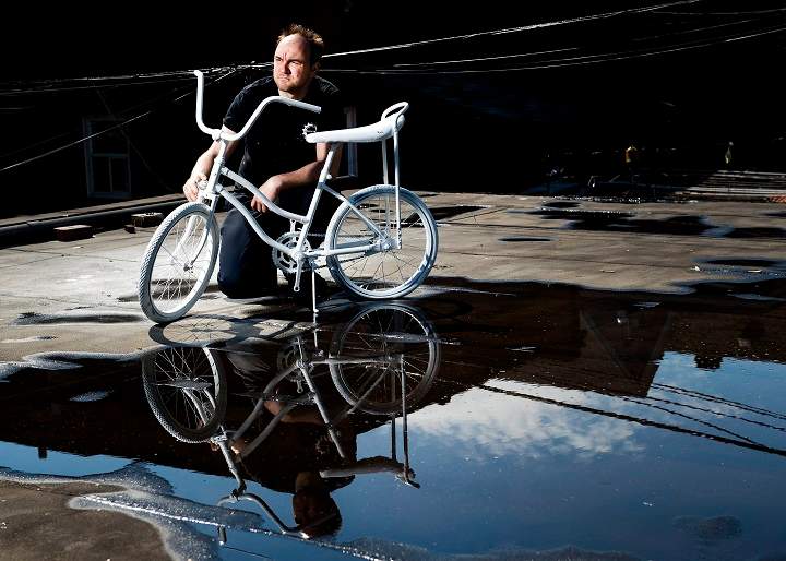 Geoffrey Bercarich poses for a photograph with the ghost bike he painted on roof of his apartment for a five year-old boy who died in a cycling accident in Toronto on Wednesday, May 31, 2017.