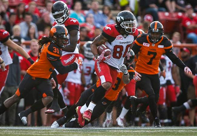 BC Lions' Josh Harris, left, and Matt Bucknor, right, look on as Calgary Stampeders' Jamal Nixon runs the ball during CFL pre-season football action in Calgary, Tuesday, June 6, 2017.
