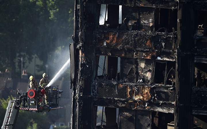 Firefighters spray water onto the Grenfell Tower block which was destroyed in a disastrous fire, in north Kensington, West London, Britain, June 16, 2017.