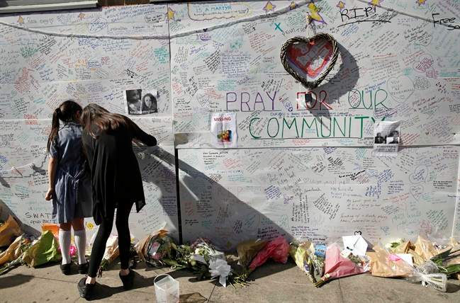 People write messages on a wall for the victims and in support for those affected by the massive fire in Grenfell Tower, in London, Thursday, June 15, 2017. 