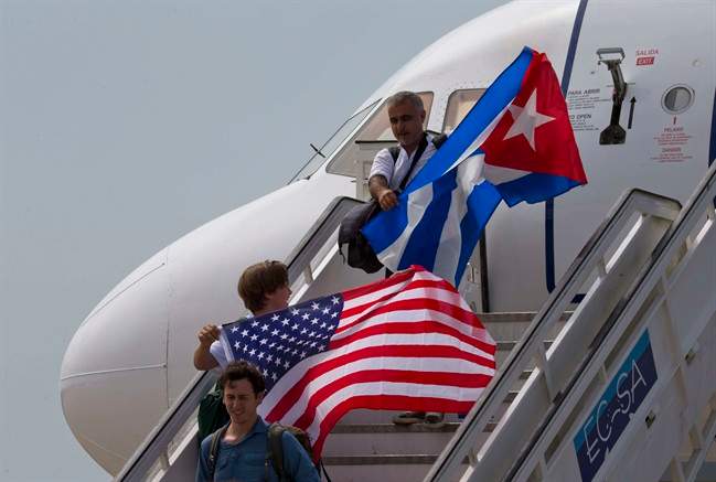 In this Aug. 31, 2016 file photo, two passengers deplane from JetBlue flight 387 waving a United States, and Cuban national flag, in Santa Clara. 