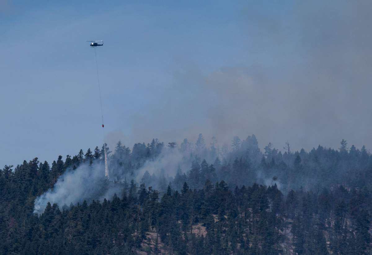 A helicopter drops water on a wildfire burning on a mountain in Ashcroft, B.C., on Sunday July 9, 2017.
