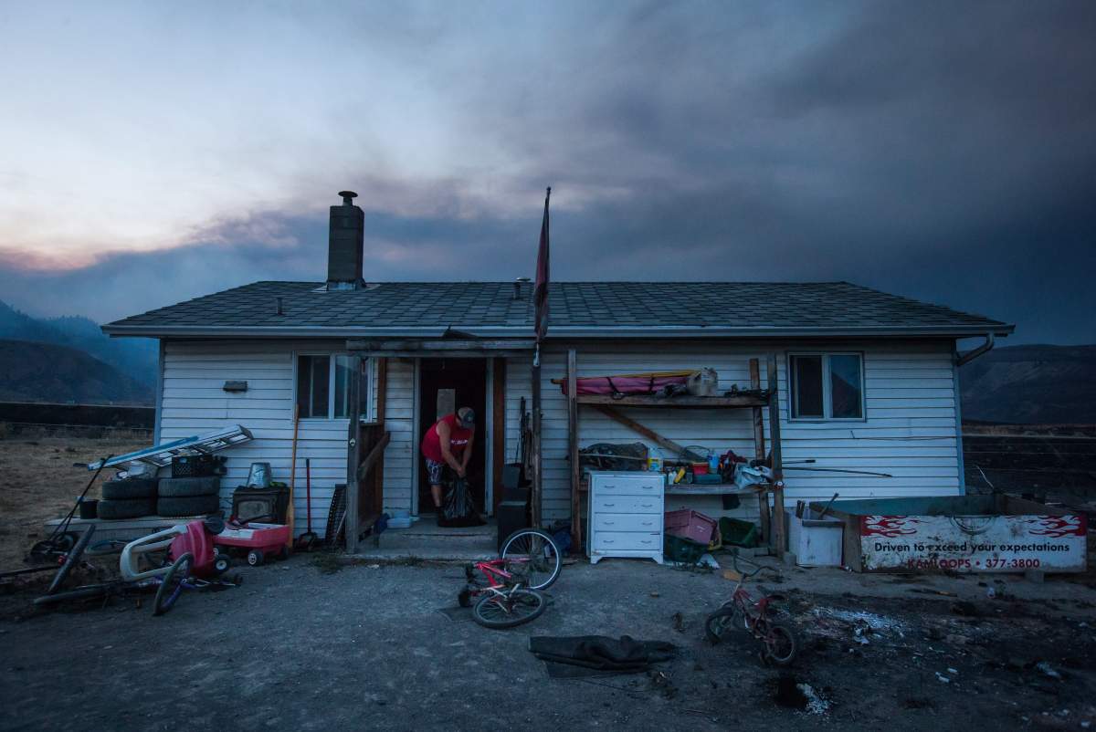Darin Minnabarriet ties a garbage bag after emptying his freezer at his house that survived a wildfire on the Ashcroft First Nation, near Ashcroft, B.C., late Sunday July 9, 2017. THE CANADIAN PRESS/Darryl Dyck
