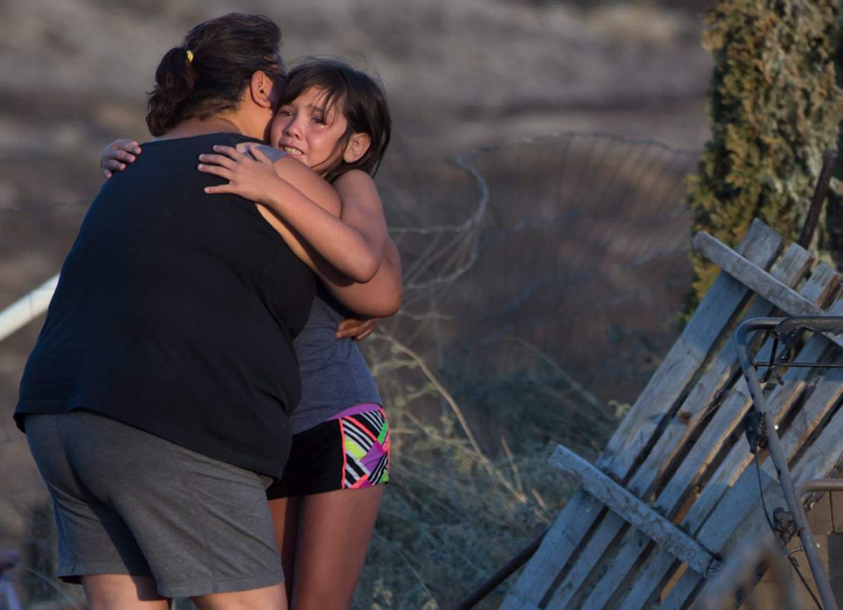Nevaeh Porter, 8, is comforted by her grandmother Angie Thorne as they view the remains of their home that was destroyed by a wildfire on the Ashcroft First Nation, near Ashcroft, B.C., July 9, 2017.
