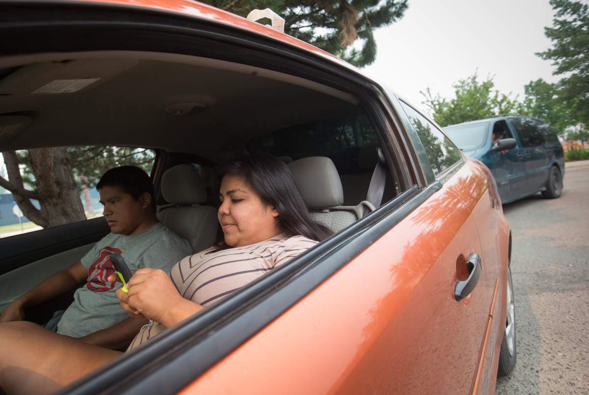 Wildfire evacuees Rebecca Terry, right, and Devon Stump, from the Cache Creek First Nation, talk to her mother on the phone while sitting in their car outside an evacuation registration centre in Kamloops, B.C., on Monday July 10, 2017. More than 200 wildfires are burning in the province and an estimated 14,000 people have been evacuated from their homes. THE CANADIAN PRESS/Darryl Dyck