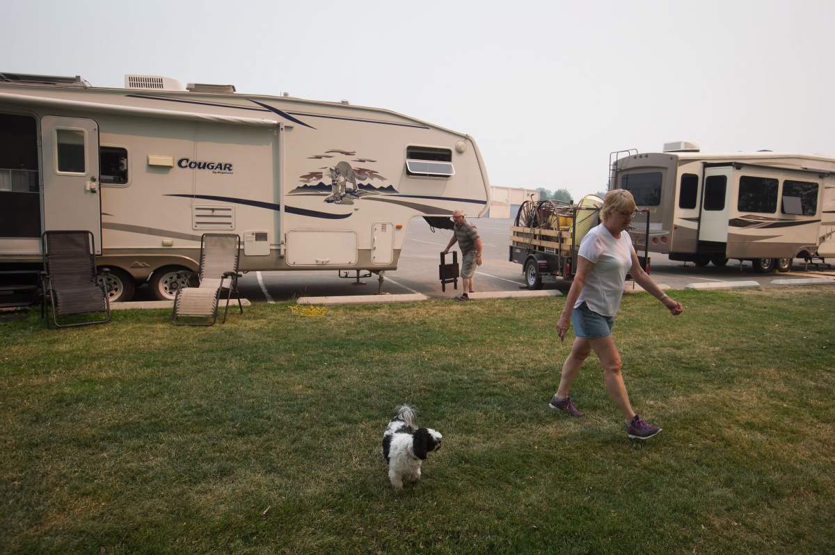 Wildfire evacuees June Leslie, front right, and her husband Ron Leslie, from Cache Creek, are seen outside their trailer where they’re staying in a parking lot in Kamloops, B.C., on Monday July 10, 2017. More than 200 wildfires are burning in the province and an estimated 14,000 people have been evacuated from their homes. THE CANADIAN PRESS/Darryl Dyck