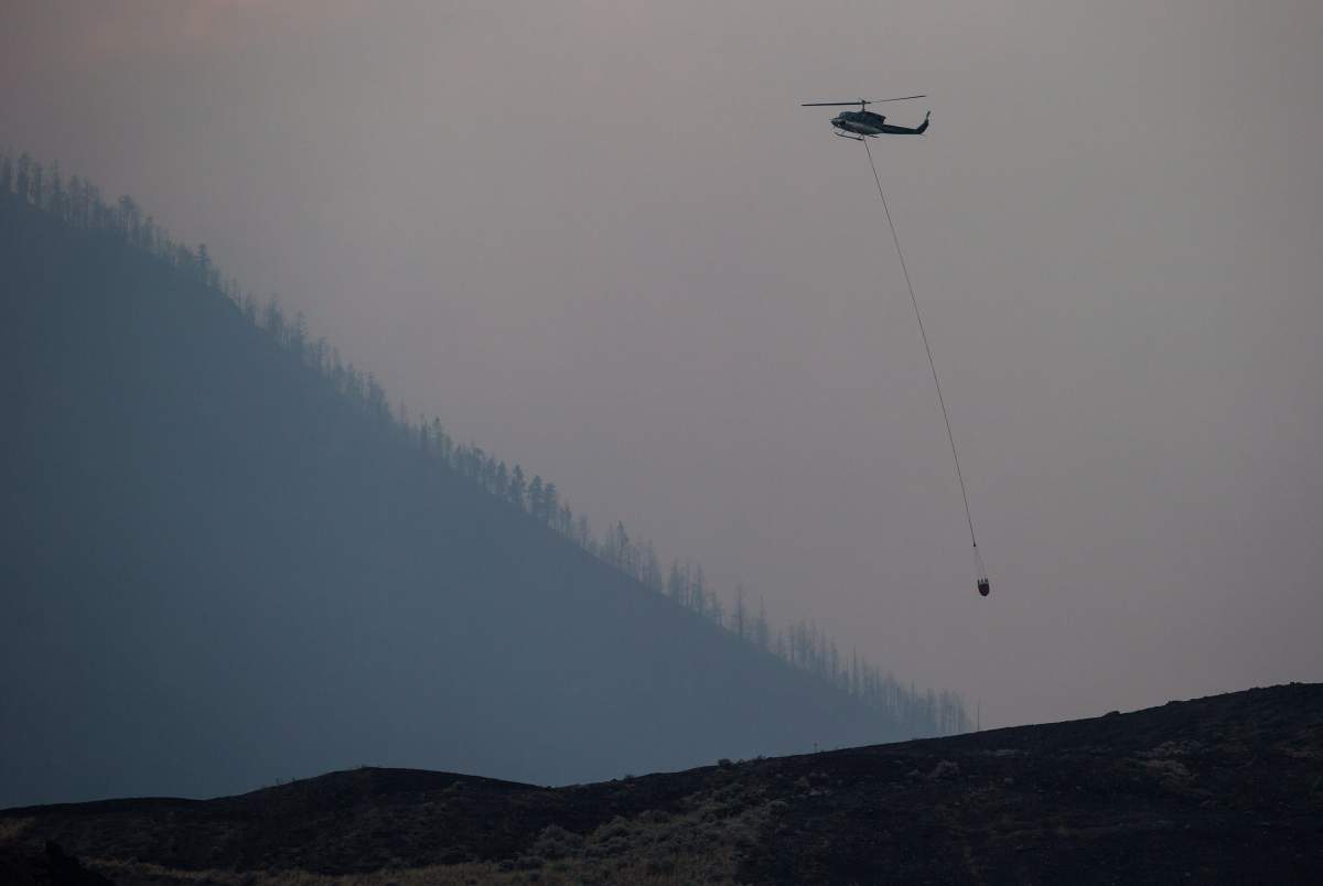 A helicopter lands while battling a wildfire burning on the top of a mountain near Ashcroft, B.C., on Monday, July 10, 2017. More than 200 wildfires are burning in the province and an estimated 14,000 people have been evacuated from their homes. THE CANADIAN PRESS/Darryl Dyck