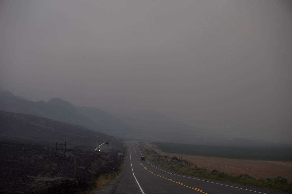 B.C. Hydro workers repair power lines that were damaged by wildfire as smoke and dirt blows in the air near Ashcroft, B.C., on Monday, July 10, 2017. More than 200 wildfires are burning in the province and an estimated 14,000 people have been evacuated from their homes. THE CANADIAN PRESS/Darryl Dyck