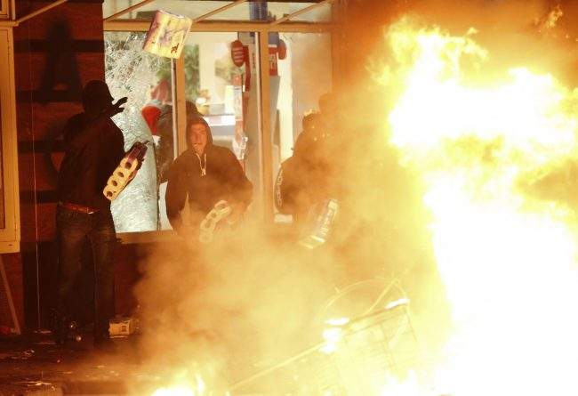 Anti-G20 protesters throw paper towels into a fire after looting them from a shop in the Hamburg Schanze district following clashes with German riot police in Hamburg, Germany, July 7, 2017. REUTERS/Hannibal Hanschke
