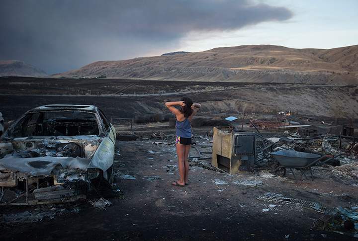 Nevaeh Porter, 8, reacts while viewing the remains of her home where she lived with her mom and grandparents that was destroyed by wildfire on the Ashcroft First Nation, B.C., late Sunday July 9, 2017.