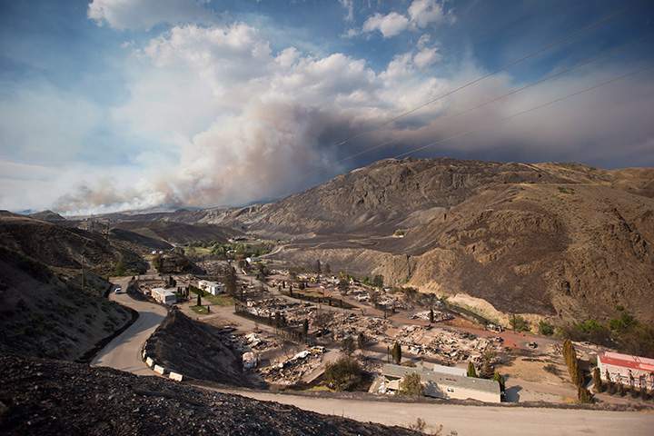The remains of mobile homes destroyed by wildfire are seen in Boston Flats as a fire burns on a mountain near Ashcroft, B.C., on Sunday, July 9, 2017.