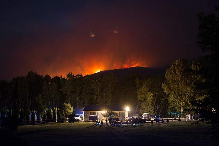A wildfire burns on a mountain behind a home in Cache Creek, B.C., in the early morning hours of Saturday July 8, 2017.
