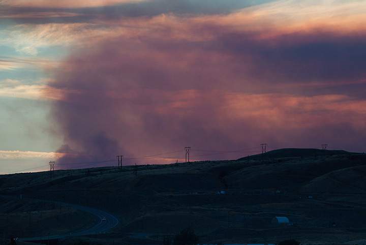 A motorist travels east on the Trans-Canada Highway in Savona, B.C., as smoke from a wildfire burning near Ashcroft rises in the distance at sunset on Friday July 7, 2017.