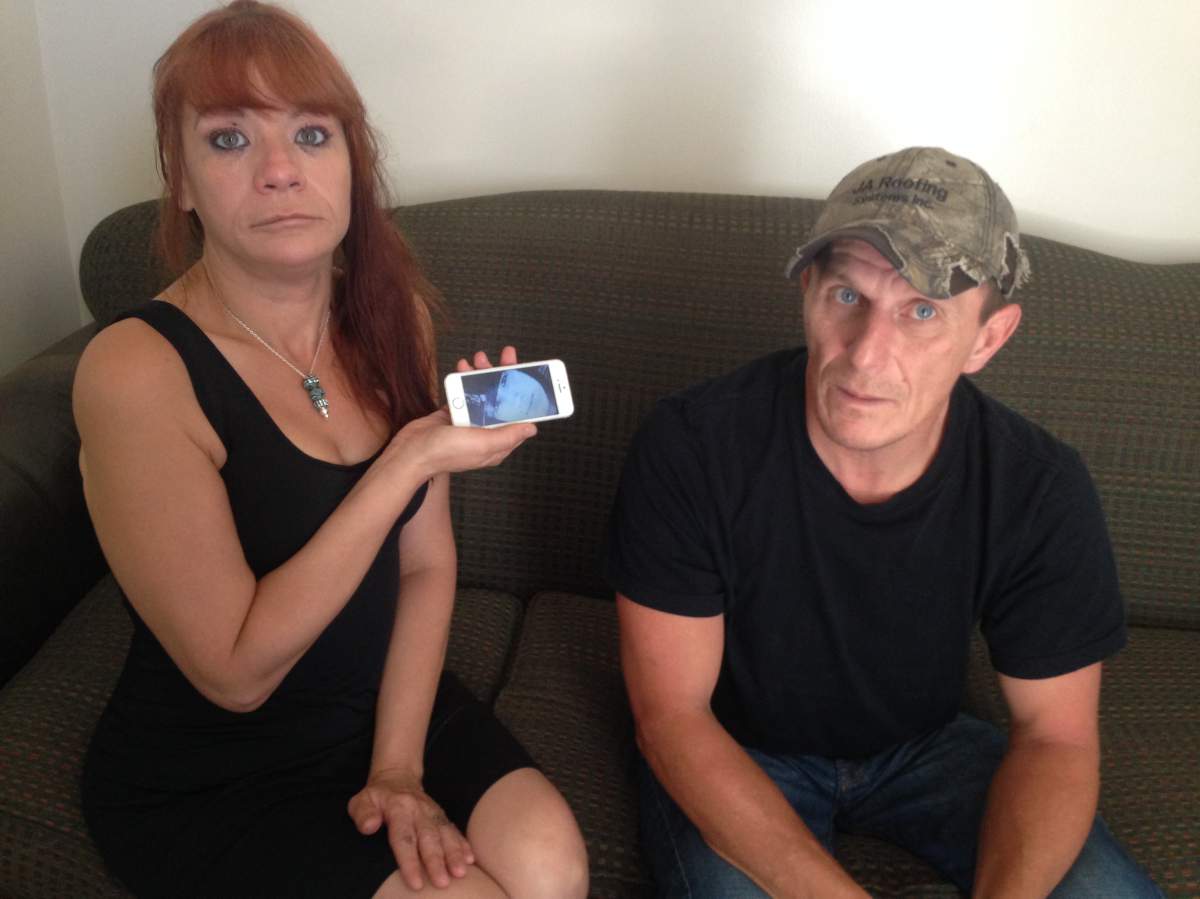 Rhonda Belcourt sits next to her boyfriend, holding her phone with a picture of her son Jade, who died in May 2017.