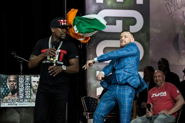 Conor McGregor, right, throws an Irish flag at Floyd Mayweather during a promotional tour stop in Toronto on Wedneday, July 12, 2017, for their upcoming boxing match in Las Vegas. 
