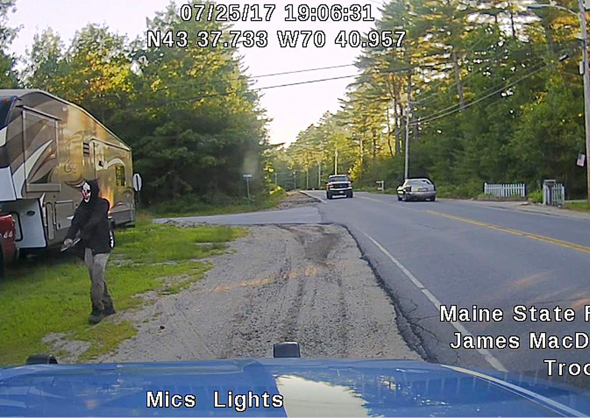 This Tuesday, July 25, 2017 patrol car dashboard camera image released by the Maine State Police shows a man strolling down a street in Hollis, Maine, who police said was wearing a clown mask with a machete taped to his amputated arm.