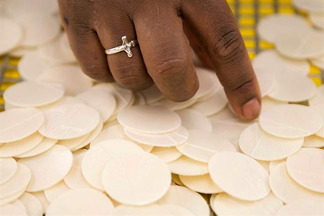 A person picks up a piece of altar bread.
