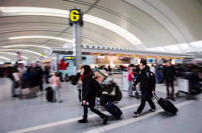 People carry luggage at Pearson International Airport in Toronto on December 20, 2013. 