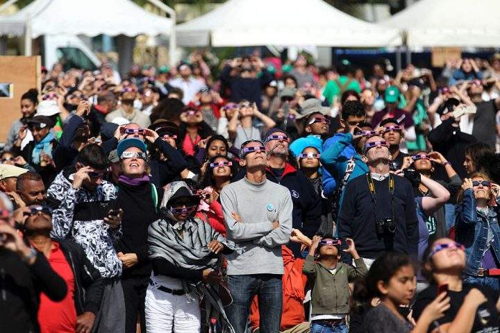 People look through eclipse viewing glasses, telescopes or photo cameras an annular solar eclipse, on September 1, 2016, in Saint-Louis, on the Indian Ocean island of La Reunion.