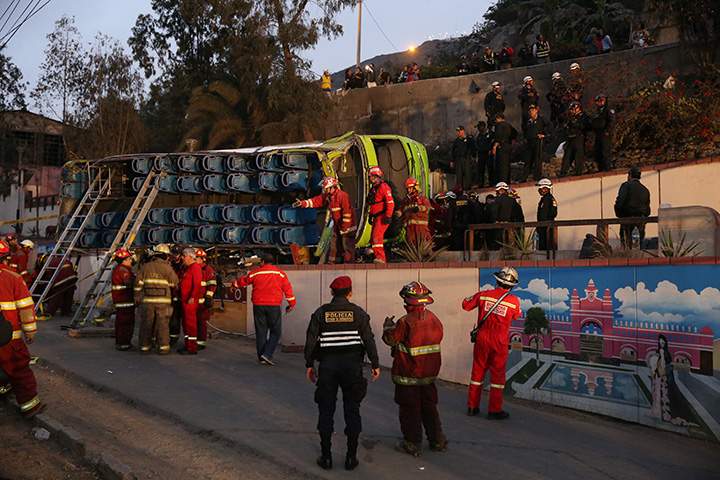 Police officers, firemen and rescue personnel inspect a double-decker tourist bus after it crashed near the tourist site of San Cristobal in Lima, Peru, July 9, 2017.