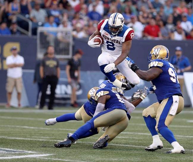 Montreal Alouettes slotback Nik Lewis (8) hurdles Winnipeg Blue Bombers linebacker Kyle Knox (50) and defensive lineman Jamaal Westerman (55) before being tackled by defensive tackle Drake Nevis (92) during the first half of CFL football action in Winnipeg on Thursday, July 27, 2017.