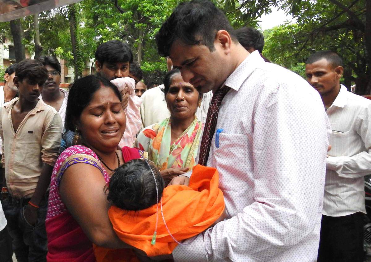 An Indian woman carries a child at the Baba Raghav Das Hospital in Gorakhpur, India, 11 August 2017 .
