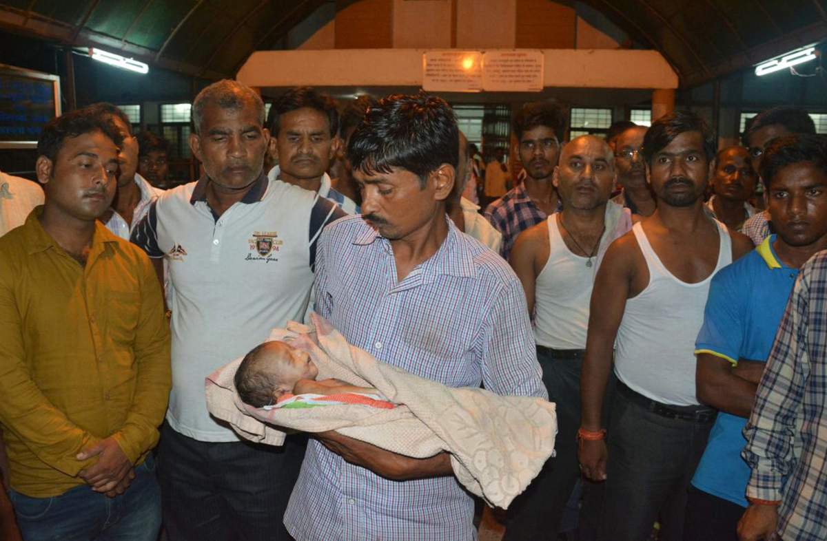 In this Friday, Aug. 11, 2017 photo, a man holds the lifeless body of his child outside Baba Raghav Das Medical College Hospital in Gorakhpur, in the northern Indian state of Uttar Pradesh.  (AP Photo)