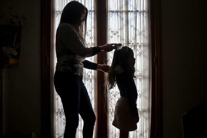 In this July 18, 2017 photo, Monica Flores combs her daughter's hair at their home in Santiago, Chile. 
