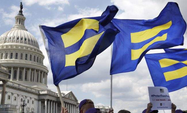 FILE - In this July 26, 2017 file photo, 

People with the Human Rights Campaign hold up "equality flags" during an event on Capitol Hill in Washington, in support of transgender members of the military

.