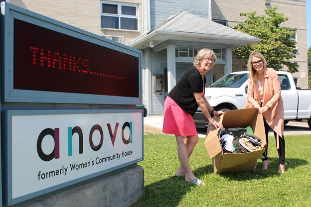 Anova executive director Kate Wiggins and Brescia's director of communications and external relations Colleen Aguilar hold a box filled with clothing donations.