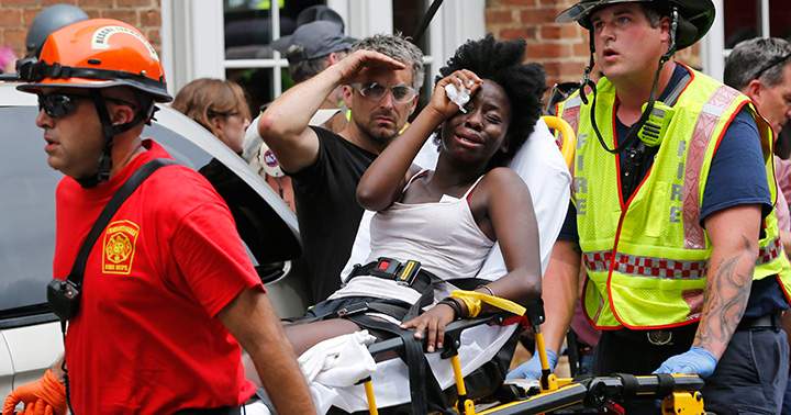 Rescue personnel help an injured woman after a car ran into a large group of protesters after awhite nationalist rally in Charlottesville, Va., Saturday, Aug. 12, 2017.