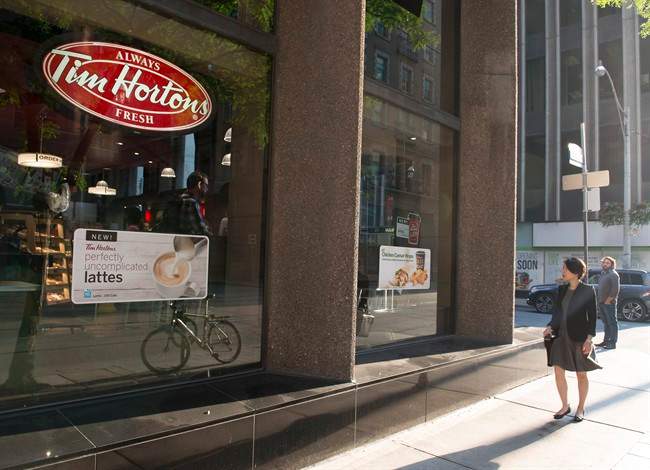 A woman walks pass a Tim Hortons in Toronto on Wednesday Aug. 2, 2017.